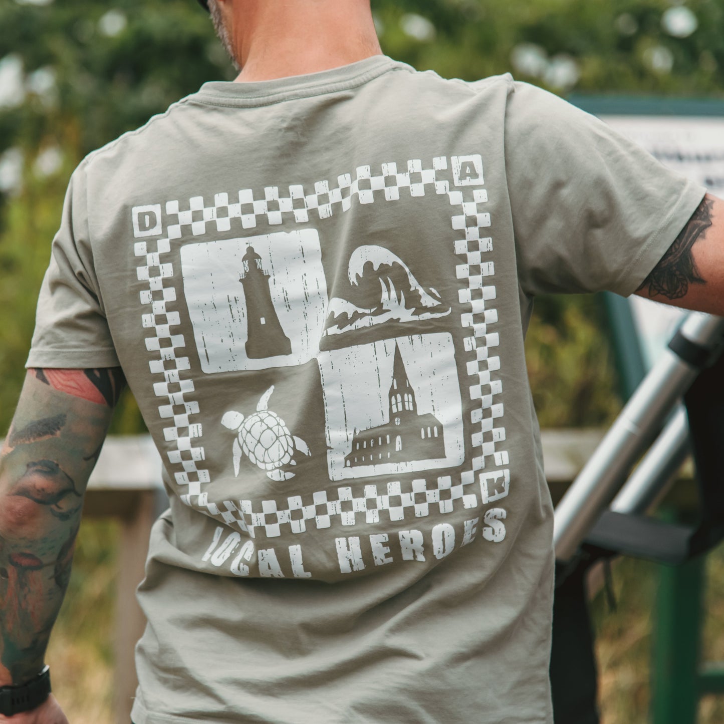 Person wearing a t-shirt with a graphic design on the back, standing outdoors.